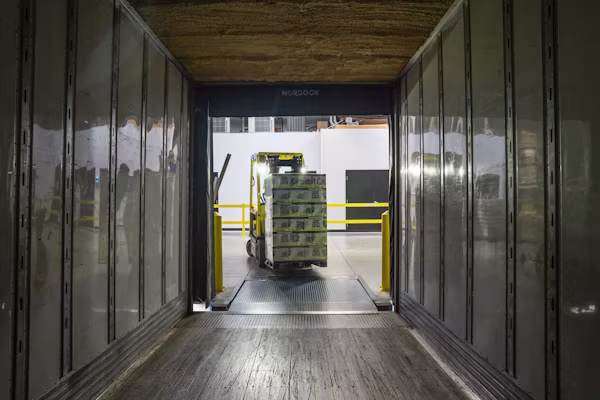 Forklift loading palletised bulk freight into a container